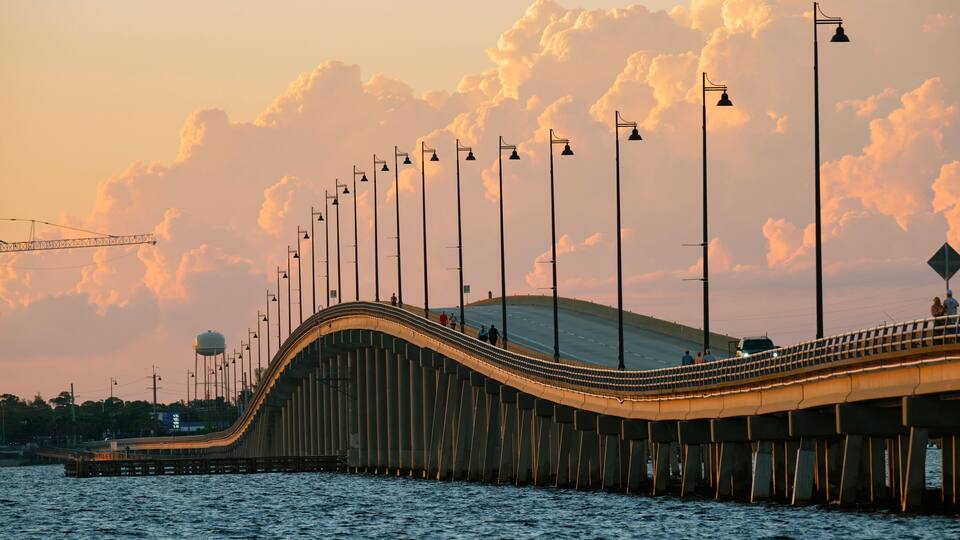 A bridge with street lamps and a water tower in the background.