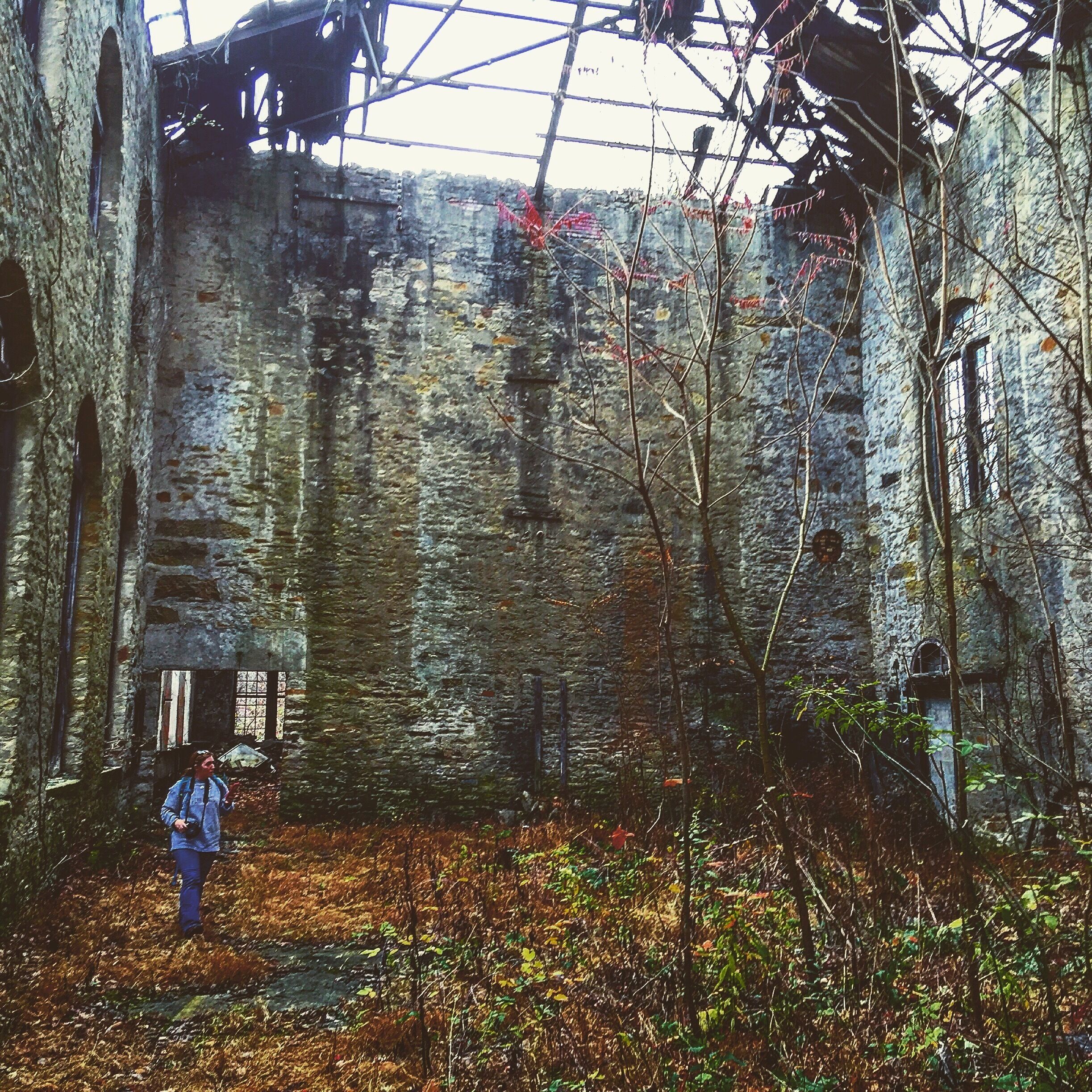 A dilapidated stone building with a collapsed roof and overgrown vegetation.