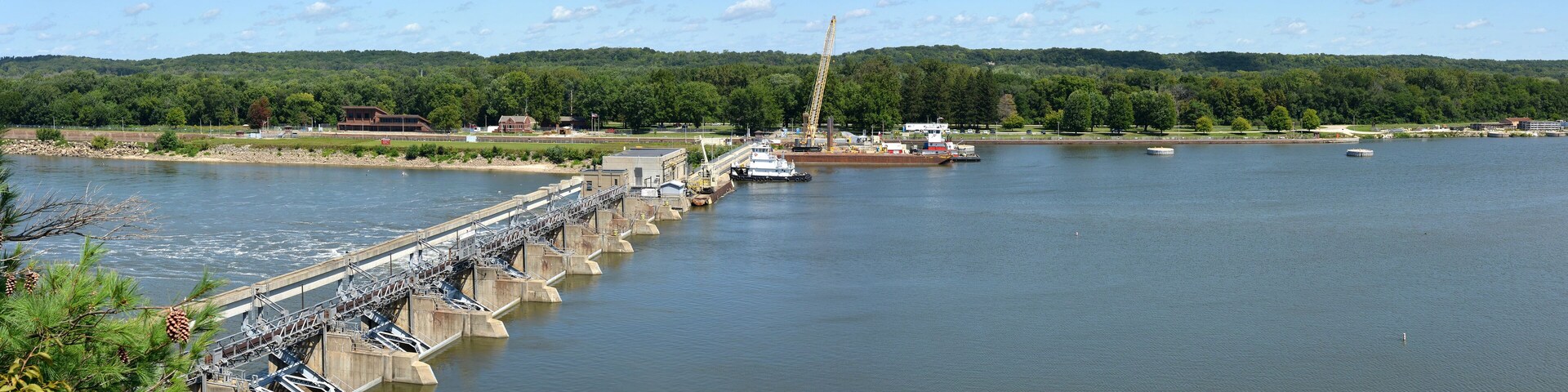 A dam with a lock system, a crane, and a boat on a river.