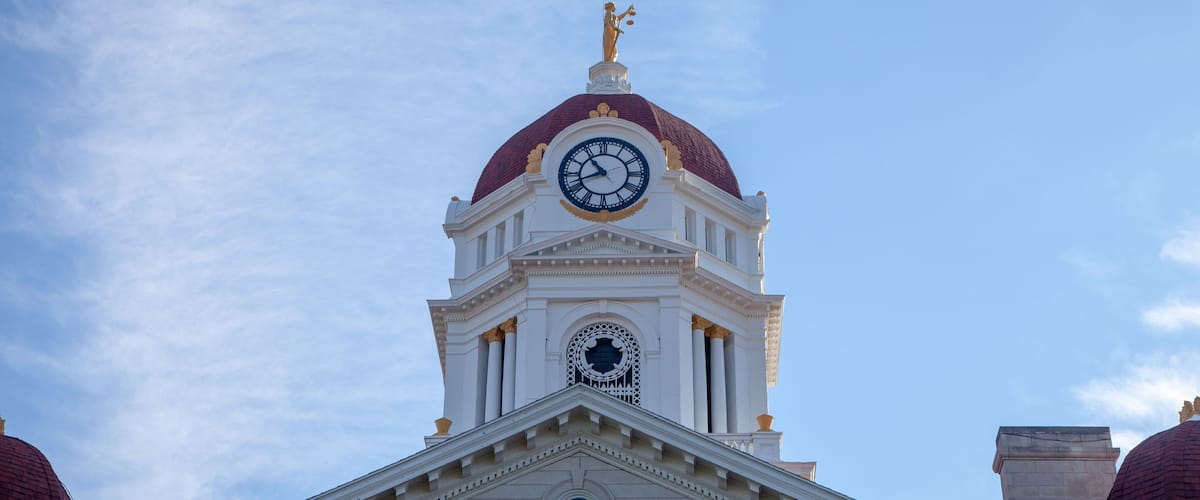 A building with a clock tower, a dome, and a statue on top.