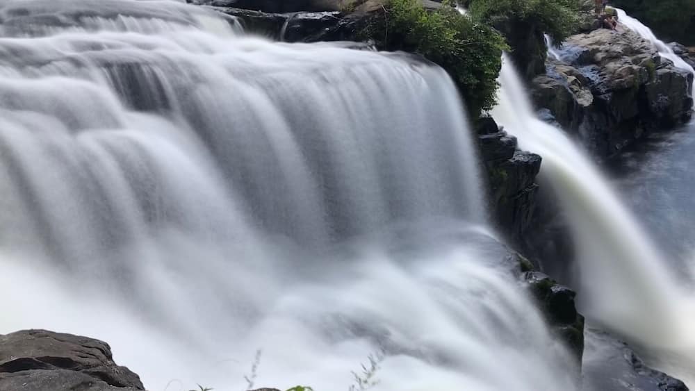 Une cascade d’eau qui dévale des rochers dans une zone boisée.