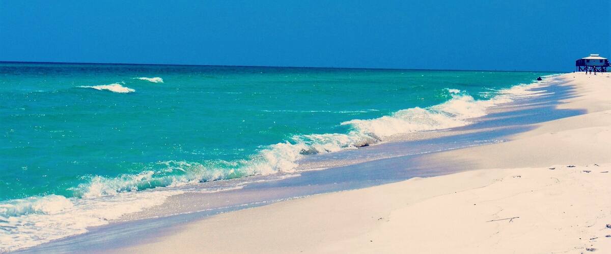 A beach with turquoise water and a lifeguard tower.