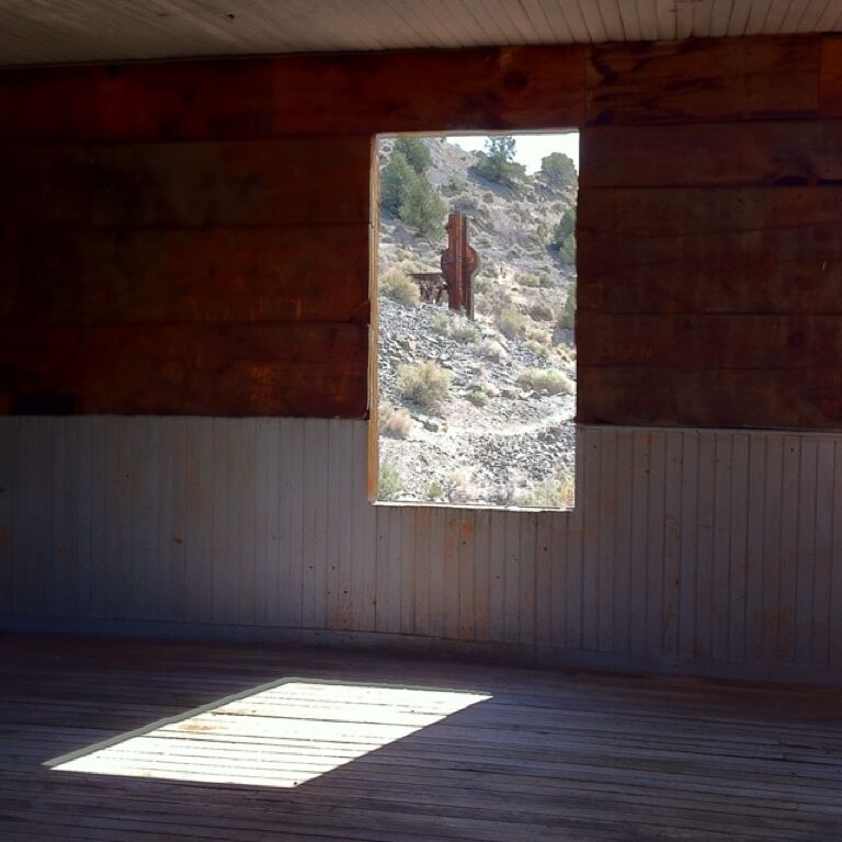 A wooden interior with a window overlooking a rocky landscape.
