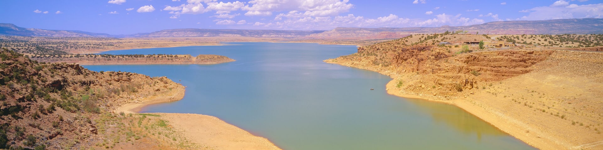 A large river winding through a desert landscape with mountains in the background and a clear blue sky.