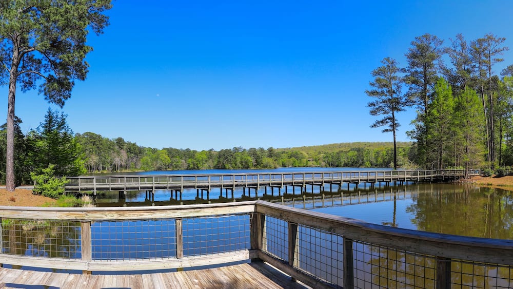 A wooden deck overlooking a calm lake with a wooden pier extending into the water.