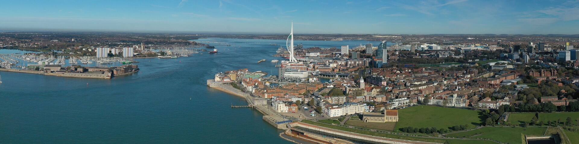 A coastal city with a prominent tower, a marina, and a river.