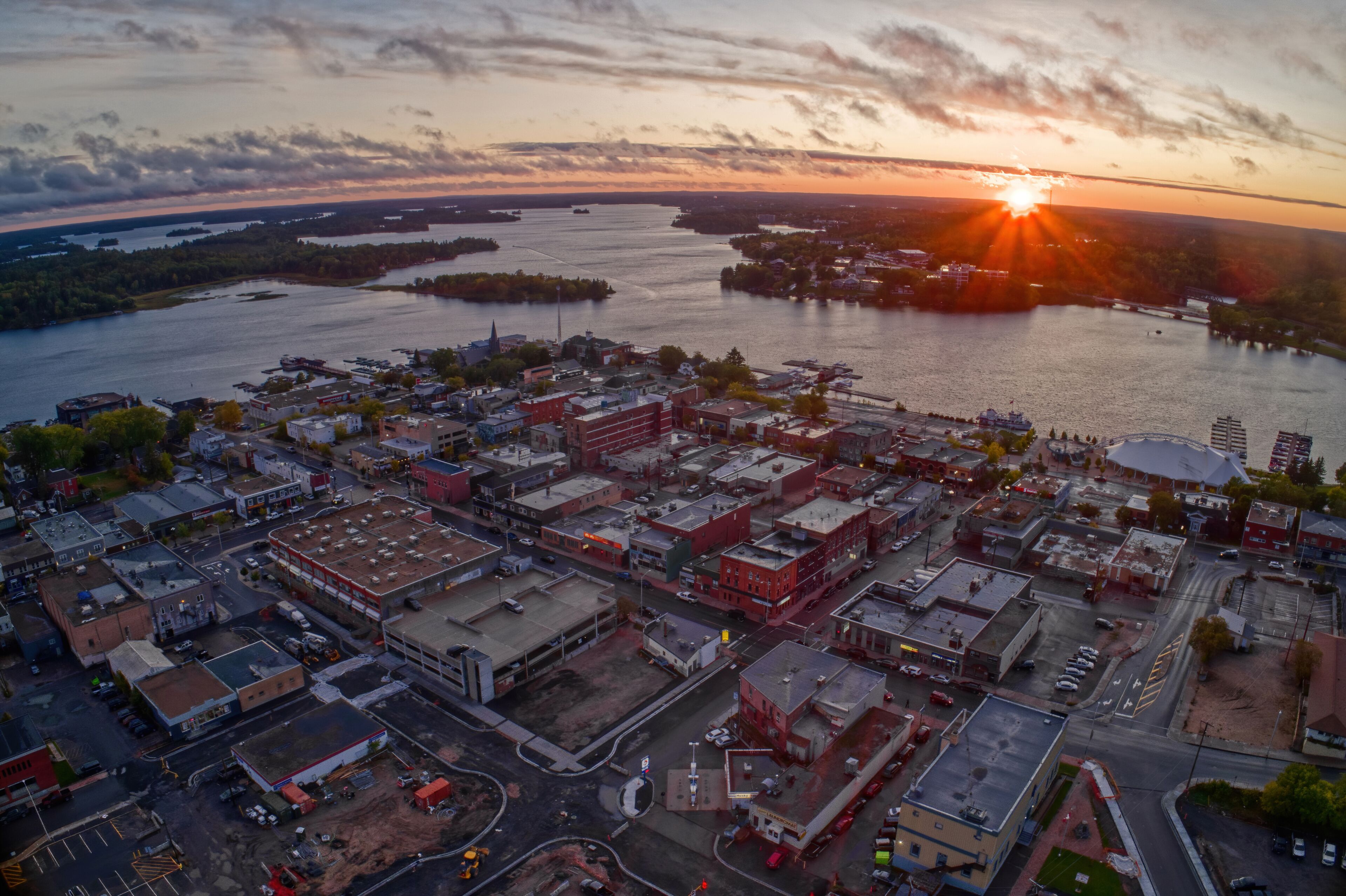 En kuststad i solnedgången, med en flod, industriella byggnader och en bro.