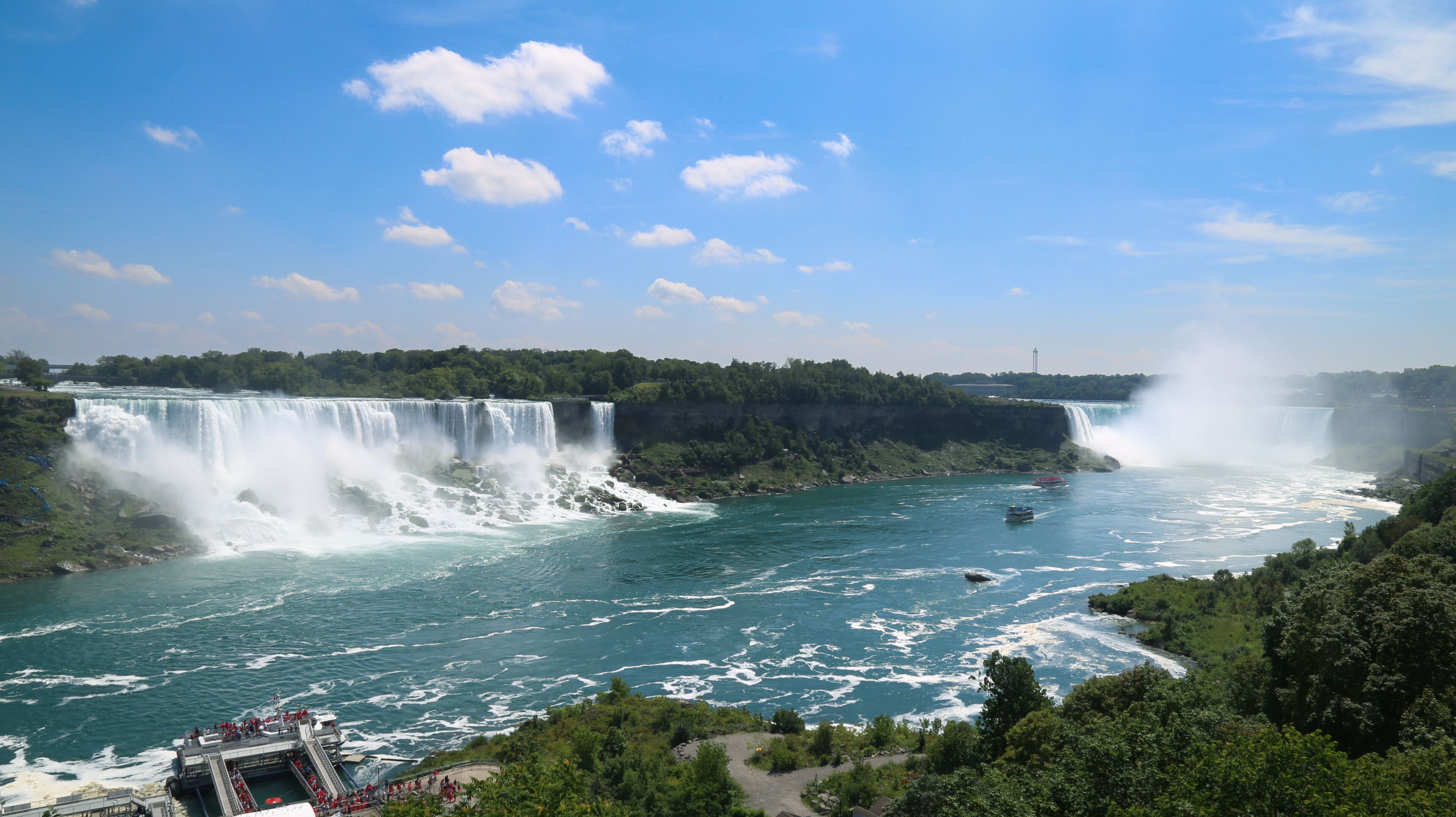 Wide view of Niagra Falls on a sunny day.