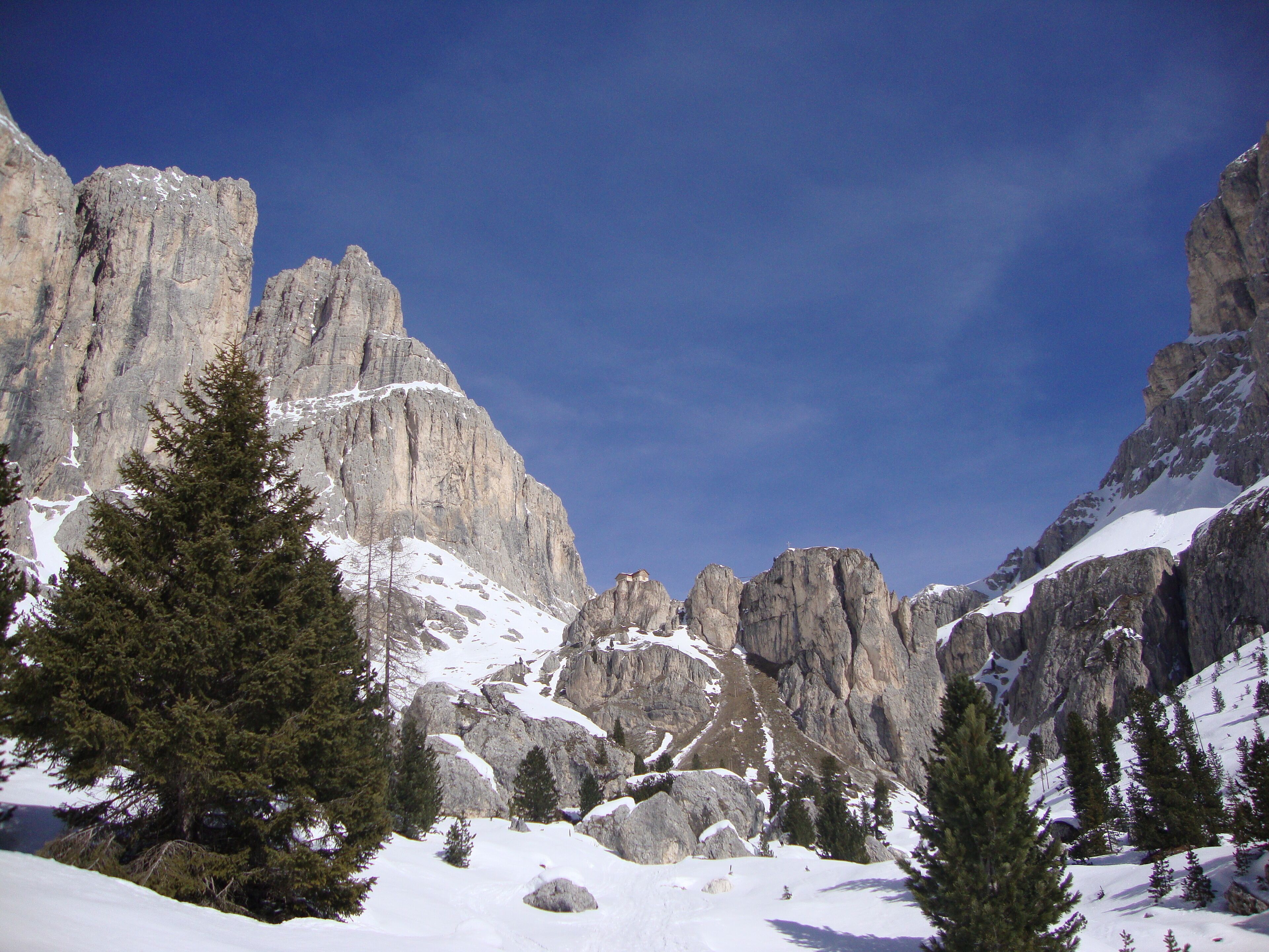 A snow-covered mountain landscape with rocky cliffs and evergreen trees.