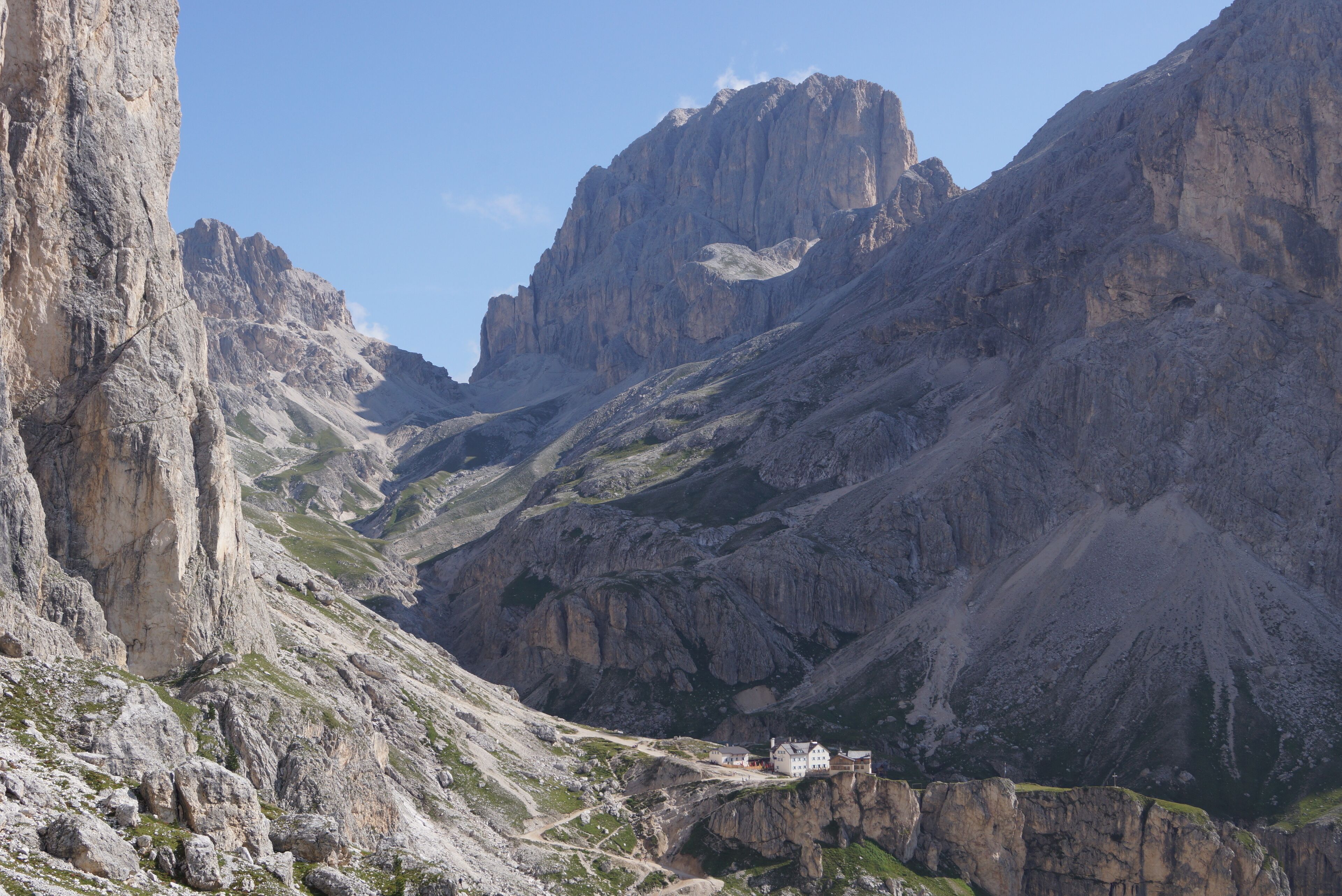 A mountain valley with rocky terrain and a small building on a cliff.