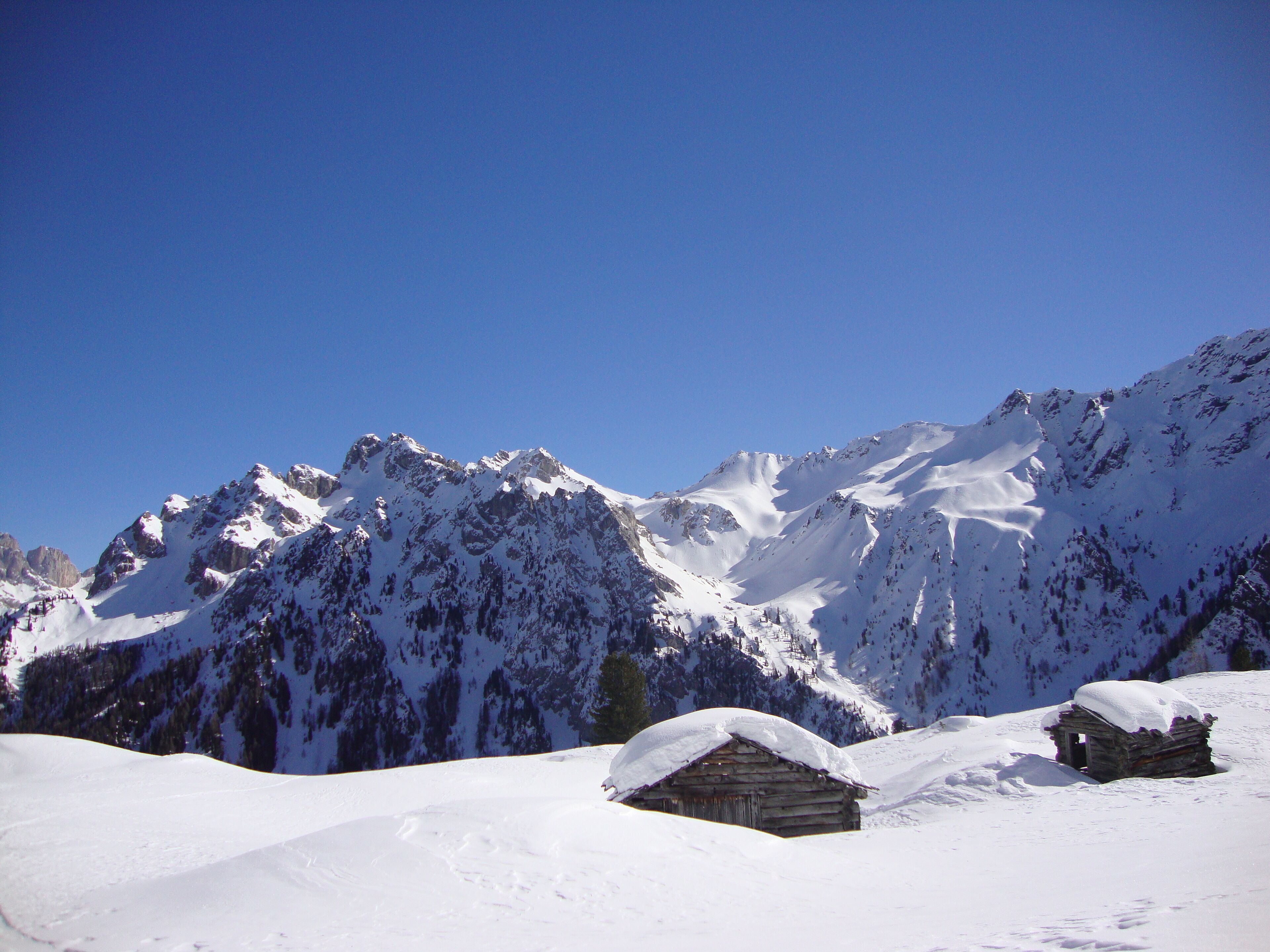 A snow-covered mountain range with a wooden cabin in the foreground.