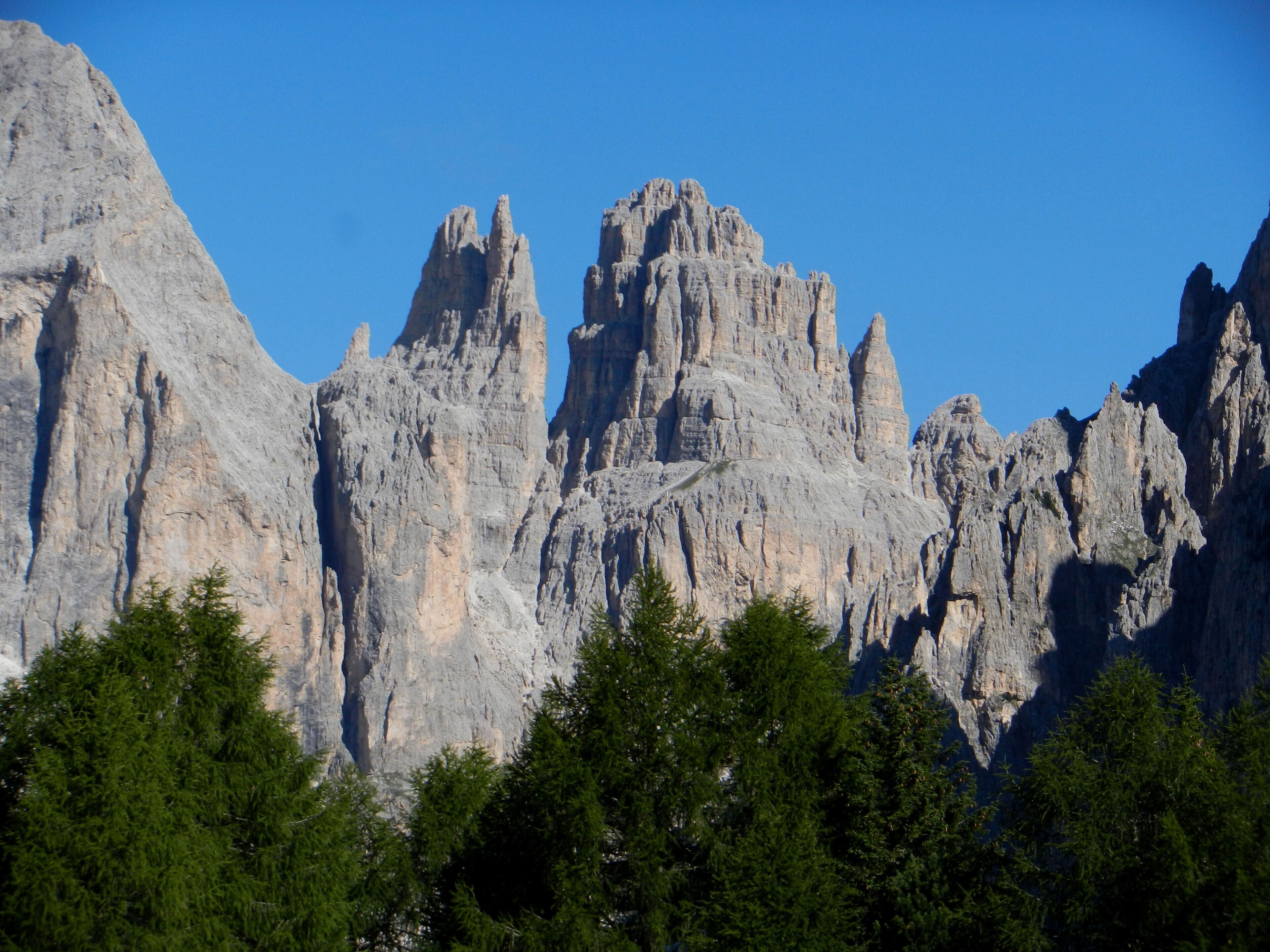 A mountain range with prominent rocky peaks and dense green forest at the base.