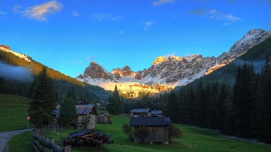 A mountainous landscape with a village, green fields, and a clear sky.