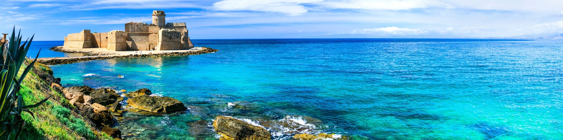 A coastal fortress surrounded by turquoise waters and clear skies.