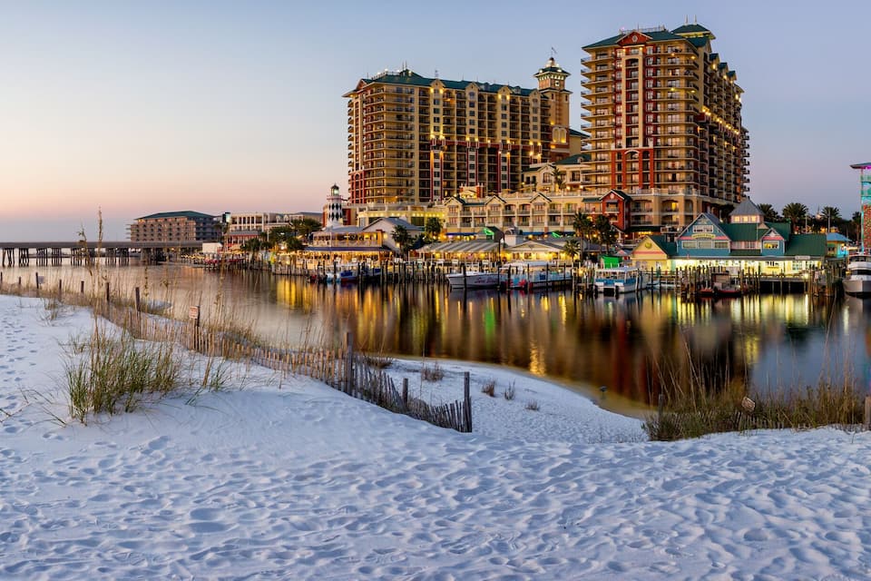 Una spiaggia innevata con un molo, edifici sul lungomare e imbarcazioni.