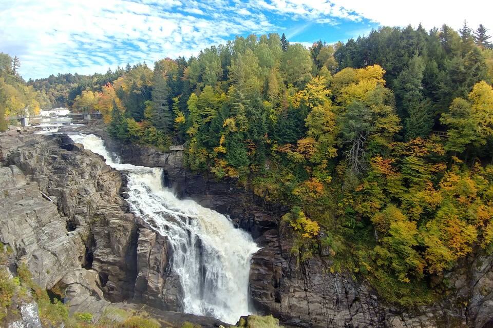 A waterfall cascading down a rocky cliff surrounded by autumn-colored trees.