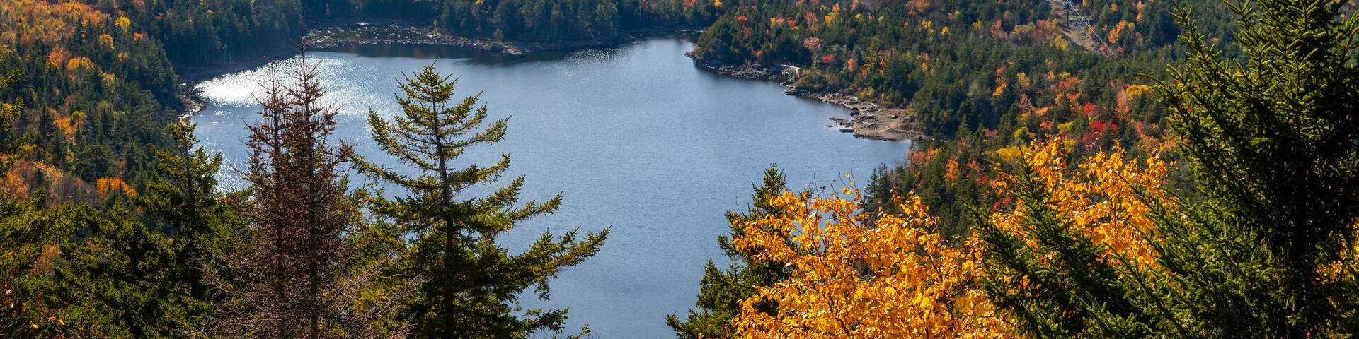 A lake surrounded by autumn-colored trees and a mountainous landscape.