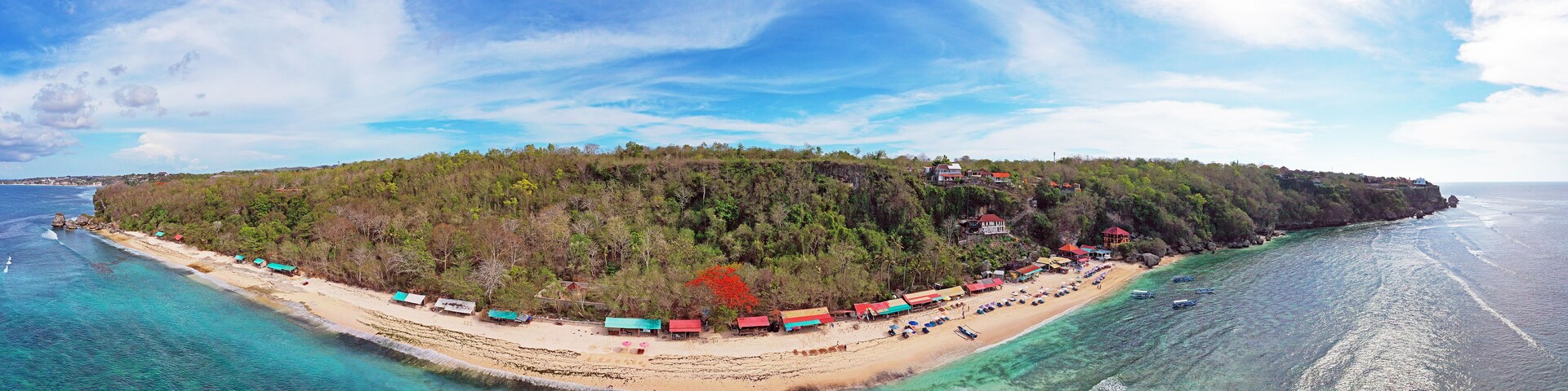 Una isla tropical con playa, aguas turquesas cristalinas y una colina boscosa.