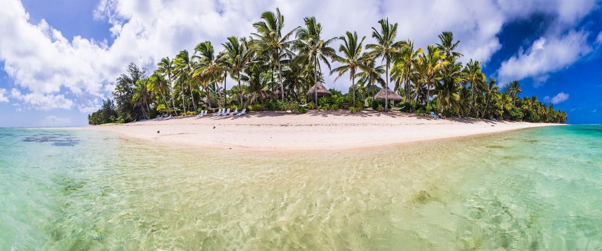 A tropical island with clear turquoise waters, white sandy beach, and palm trees.