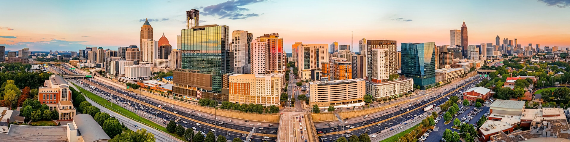 A cityscape with a mix of modern and historic buildings, a prominent highway, and a clear sky.