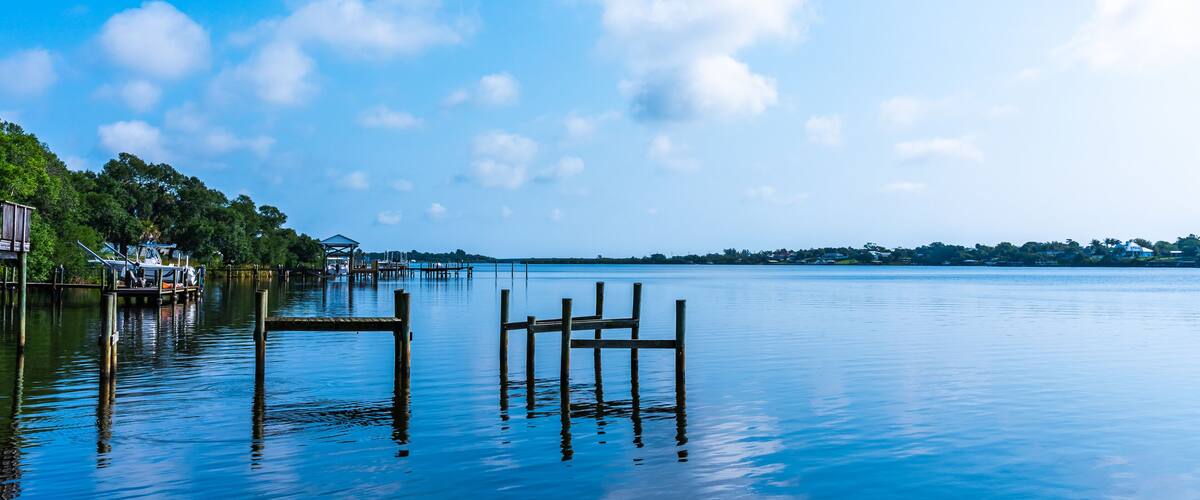 Blue water view with private wooden piers on the Sebastian River in Little Hollywood, Mikko, Florida. Panoramic photo in blue tones