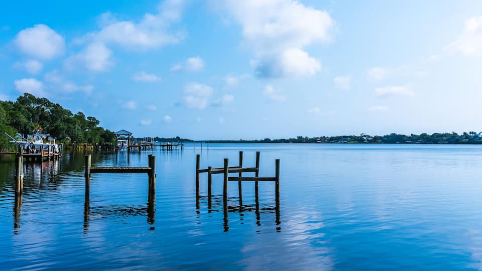 Blue water view with private wooden piers on the Sebastian River in Little Hollywood, Mikko, Florida. Panoramic photo in blue tones