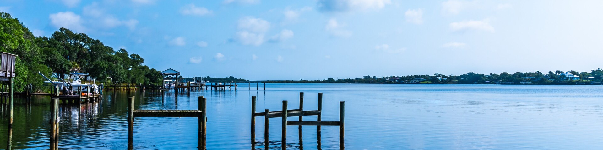 Blue water view with private wooden piers on the Sebastian River in Little Hollywood, Mikko, Florida. Panoramic photo in blue tones