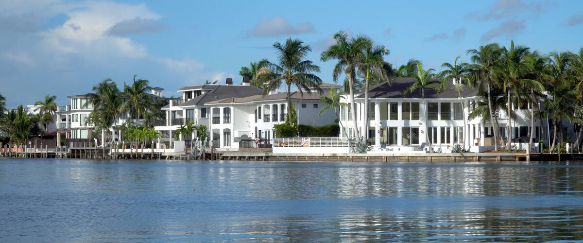 Typical luxury riverfront summer homes along quiet river in tropical southern location on beautiful summer day. Exterior generic establishing shot