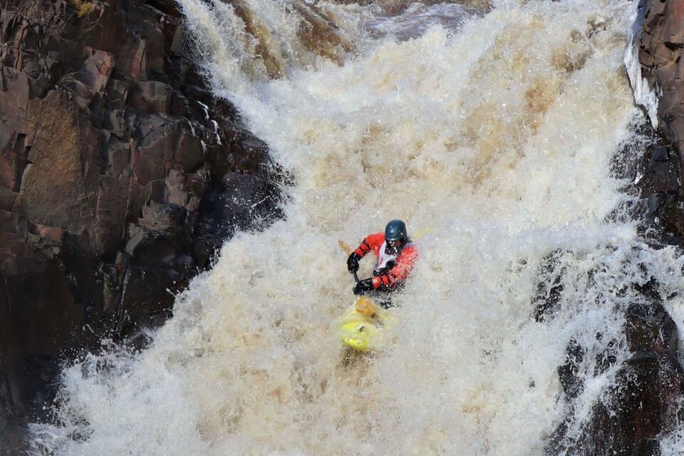 A kayaker navigating a turbulent waterfall.