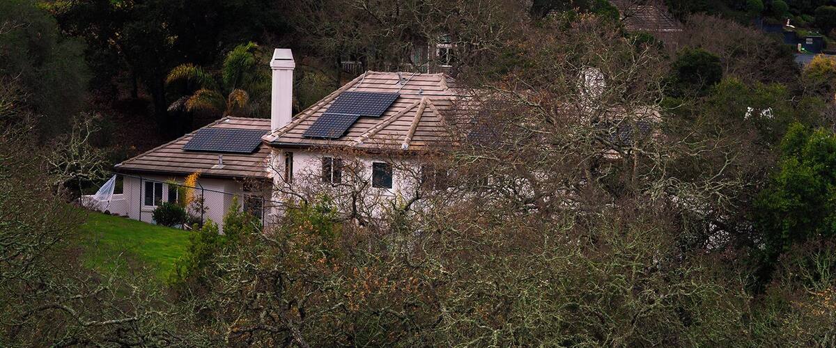 A house surrounded by dense forest and hills.