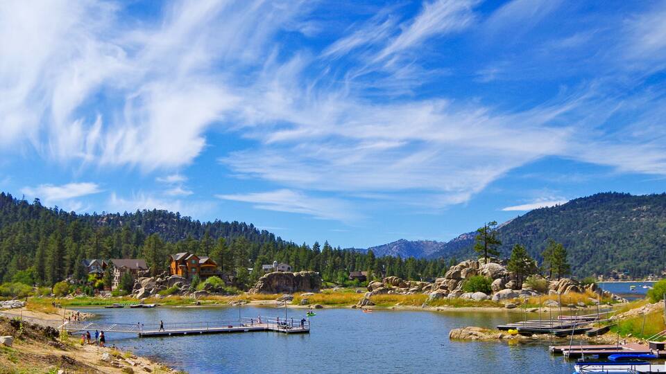 Panoramic view of Big Bear Lake in southern California with lakeside houses and people canoeing and kayaking