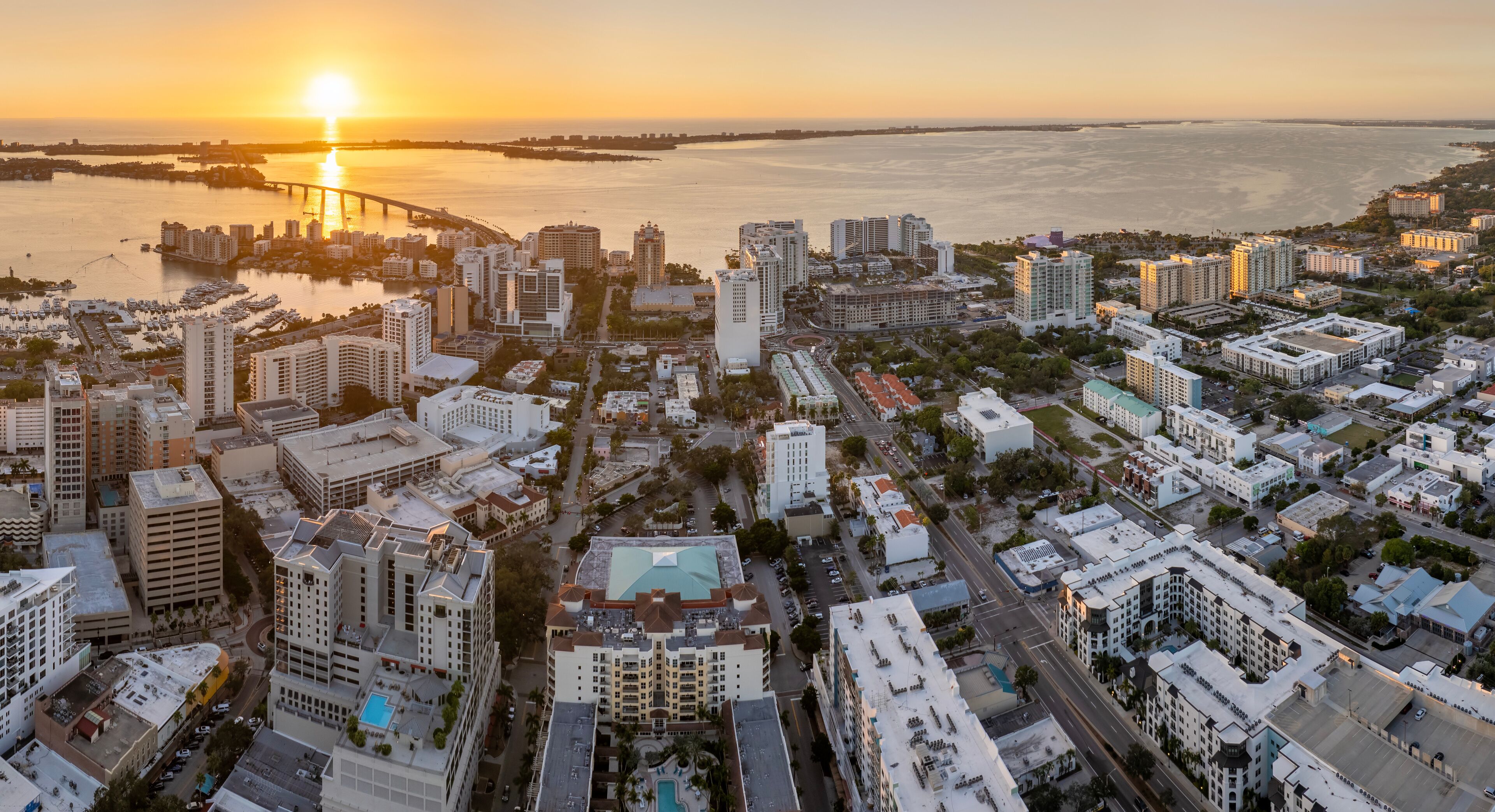 Aerial view of Sarasota city downtown at sunset with high-rise office buildings and Ringling Bridge on horizon. Real estate development in Florida. USA travel destination