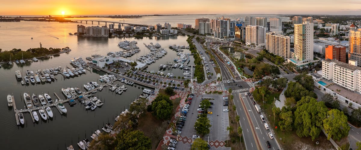 Above view of Sarasota city, Florida with yachts in bay harbor and waterfront office high-rise buildings. Development of housing and transportation in the US