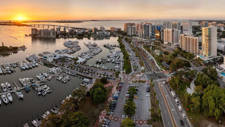 Above view of Sarasota city, Florida with yachts in bay harbor and waterfront office high-rise buildings. Development of housing and transportation in the US