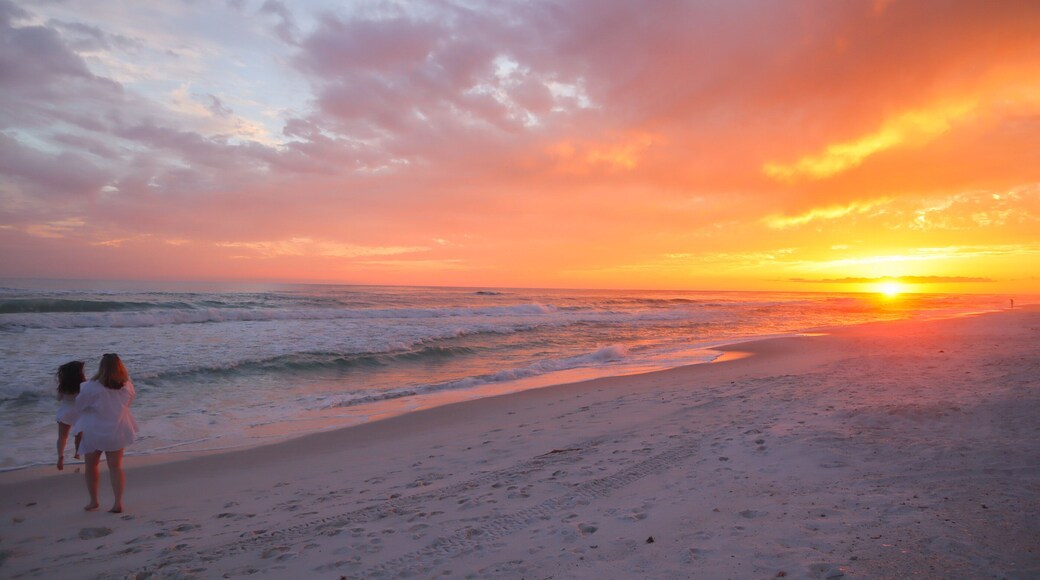 Beautiful peaceful pink orange sunset in Panama City Beach Florida and 2 girls frolicking in the sand