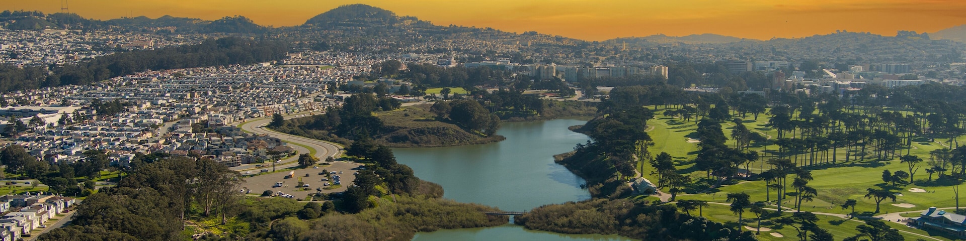 aerial shot of a beautiful spring landscape at Lake Merced with blue lake water and lush green trees, grass and plants at sunset in San Francisco California USA