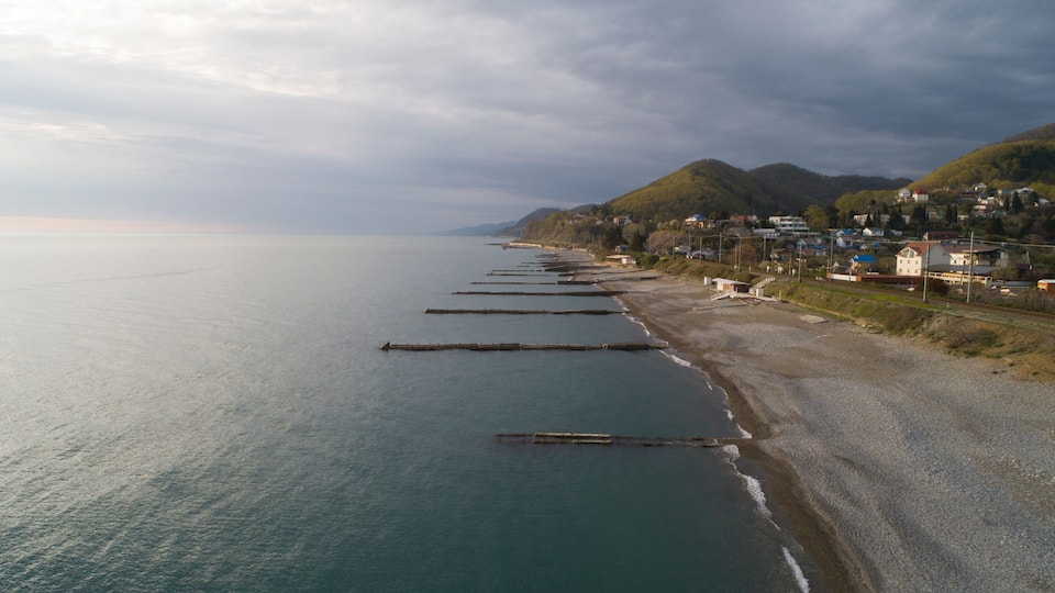 Beautiful aerial view of a coastal settlement at evening. Golovinka, Sochi. view of the highest bridge in Russia. serpentine in the mountains