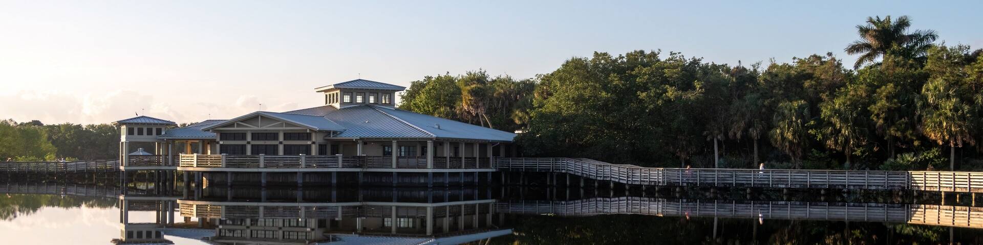 Green Cay Nature Center and Wetlands visitor pavilion in Boynton Beach, Florida reflected in calm water on clear cloudless sunny morning..