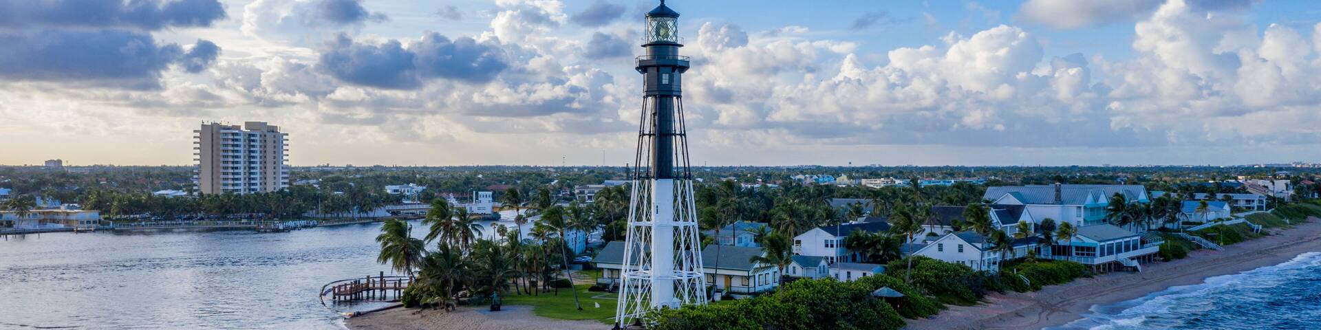 A coastal town with a prominent lighthouse, a beach, and a rocky breakwater.