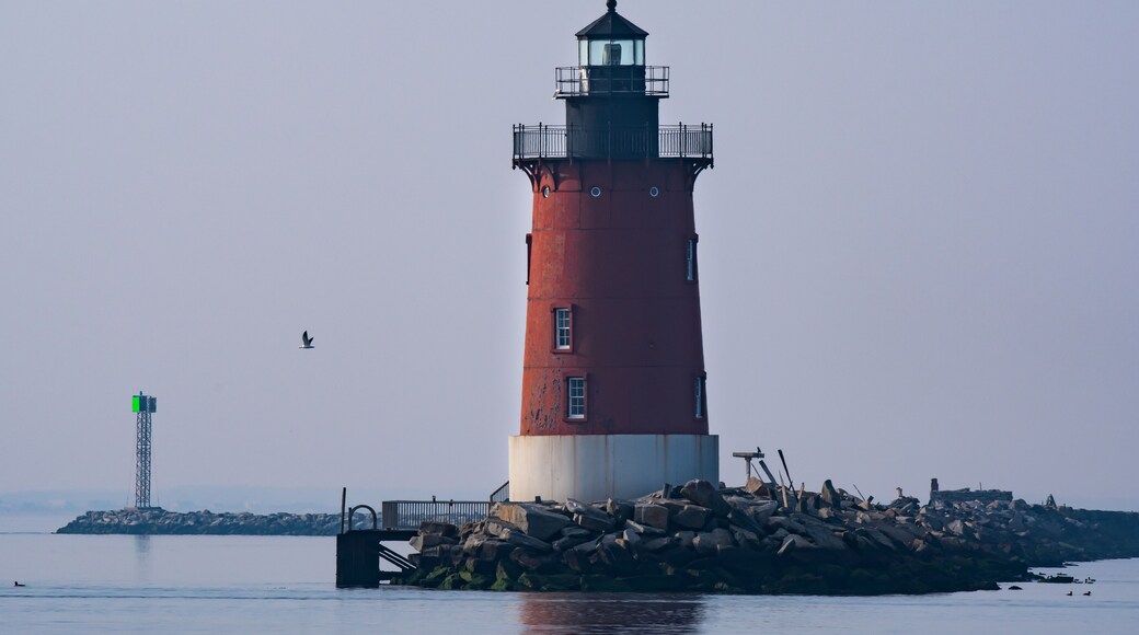 A red lighthouse on the bay in Delaware during twilight