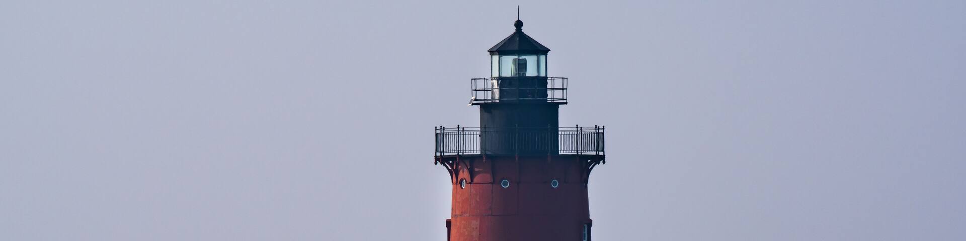 A red lighthouse on the bay in Delaware during twilight