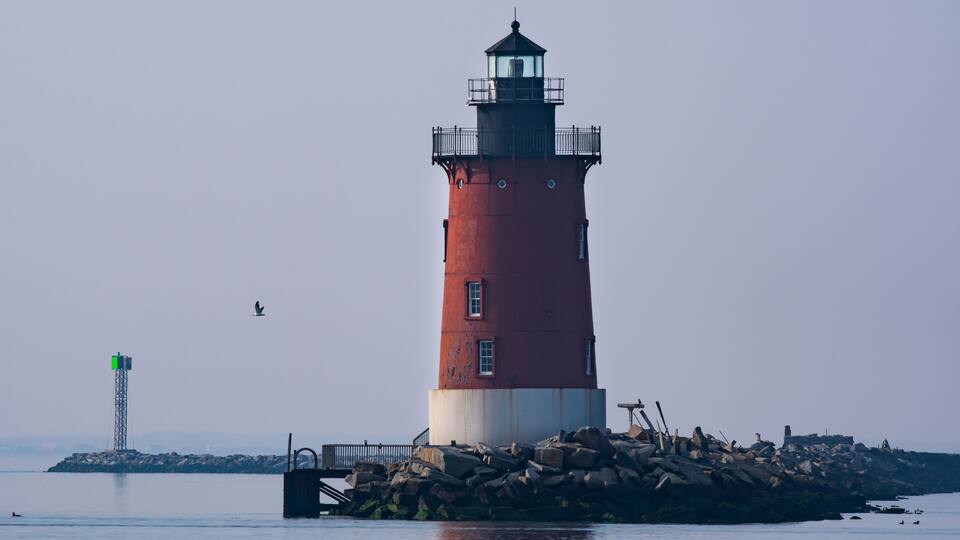 A red lighthouse on the bay in Delaware during twilight