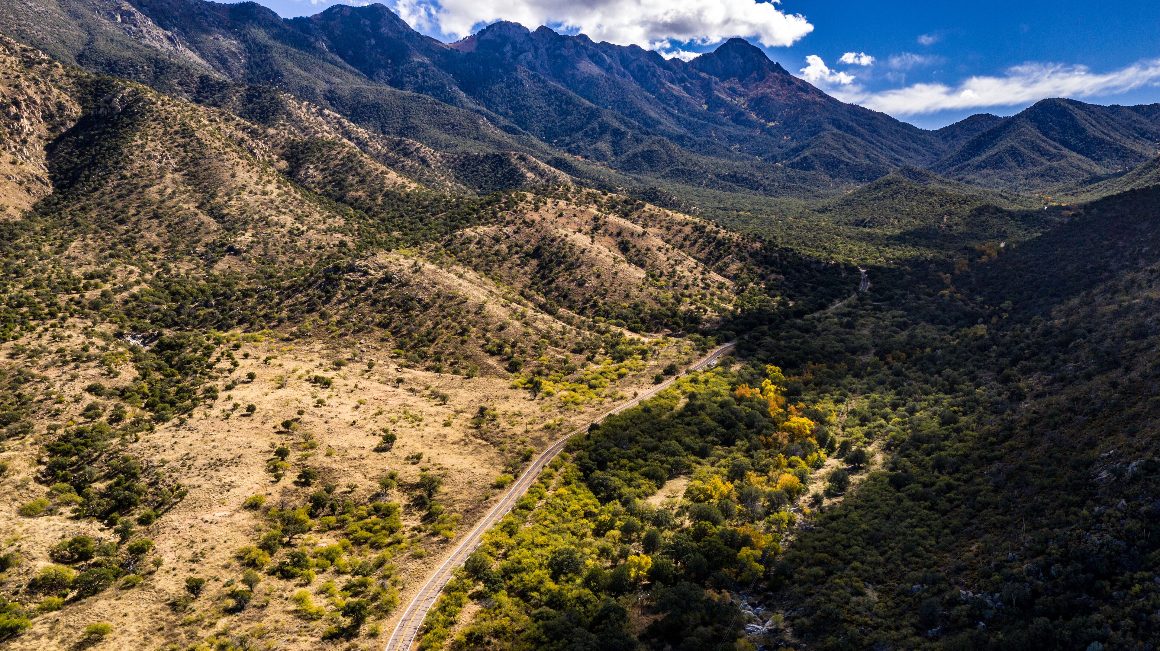 Aerial panorama of Madera Canyon in the Santa Rita Mountains, Arizona in the Fall with purple mountains, green, yellow, orange trees and bushes, blue sky