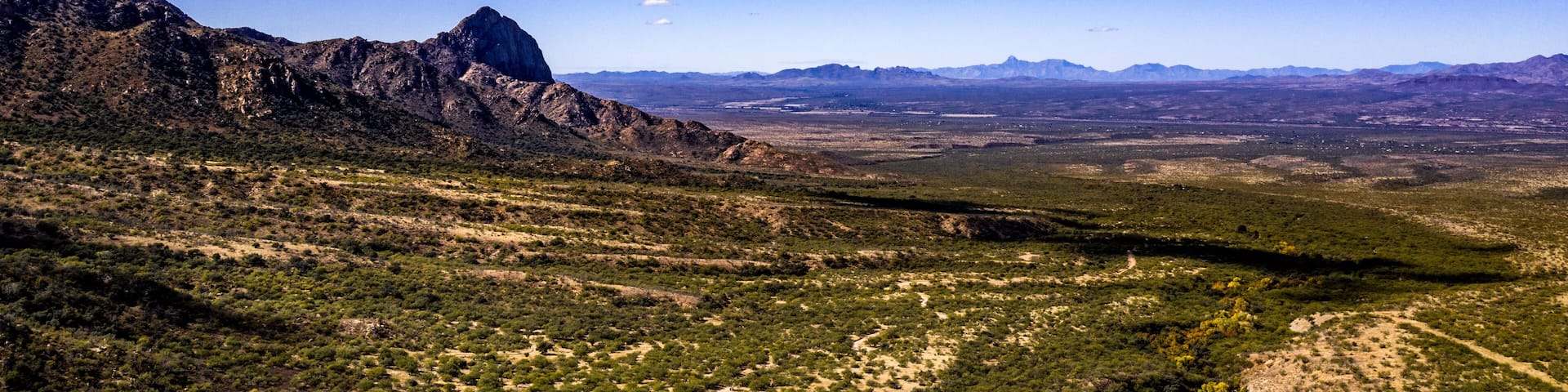 Aerial panorama of Madera Canyon in the Santa Rita Mountains, Arizona in the Fall with purple mountains, green, yellow, orange trees and bushes, blue sky