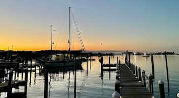 Boats moored in Silver Lake Harbor at sunset, with a pier extending into the calm water, under a gradient evening sky in Ocracoke, North Carolina.