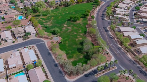 Vista aérea de una zona residencial con casas, calles y un gran campo verde.