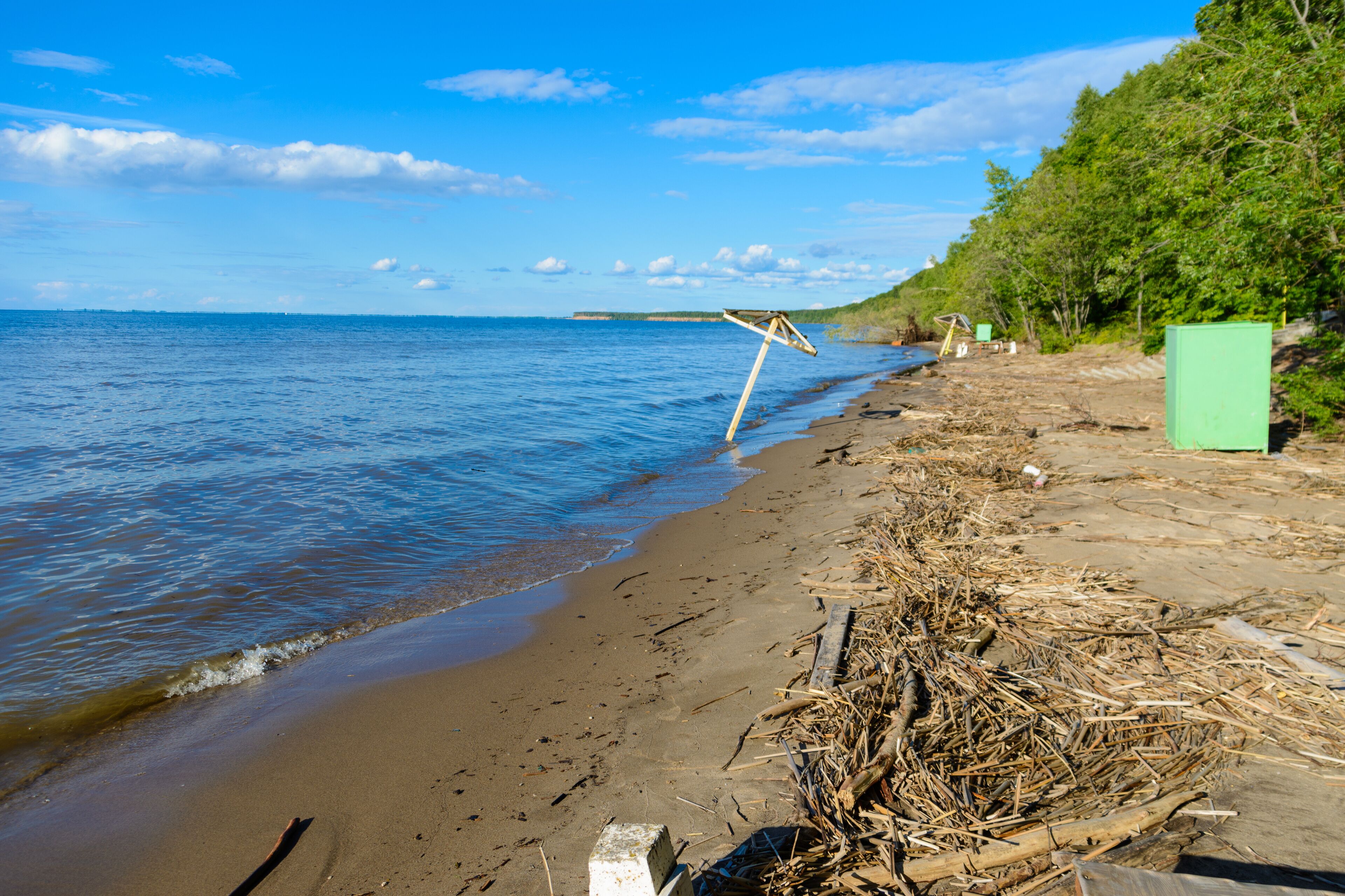 Deserted beach. Abandoned benches, umbrellas, tables, changing rooms on a sandy beach after the of summer vacation.