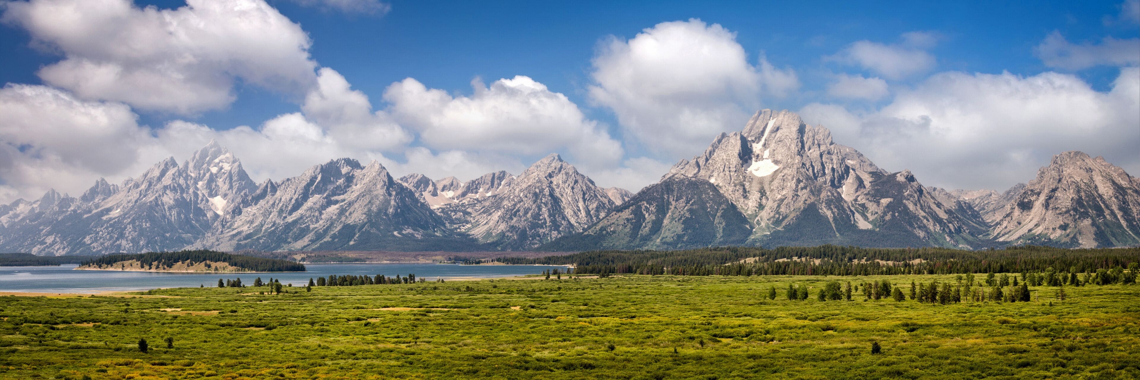 A mountain range with a lake in the foreground and a clear sky.