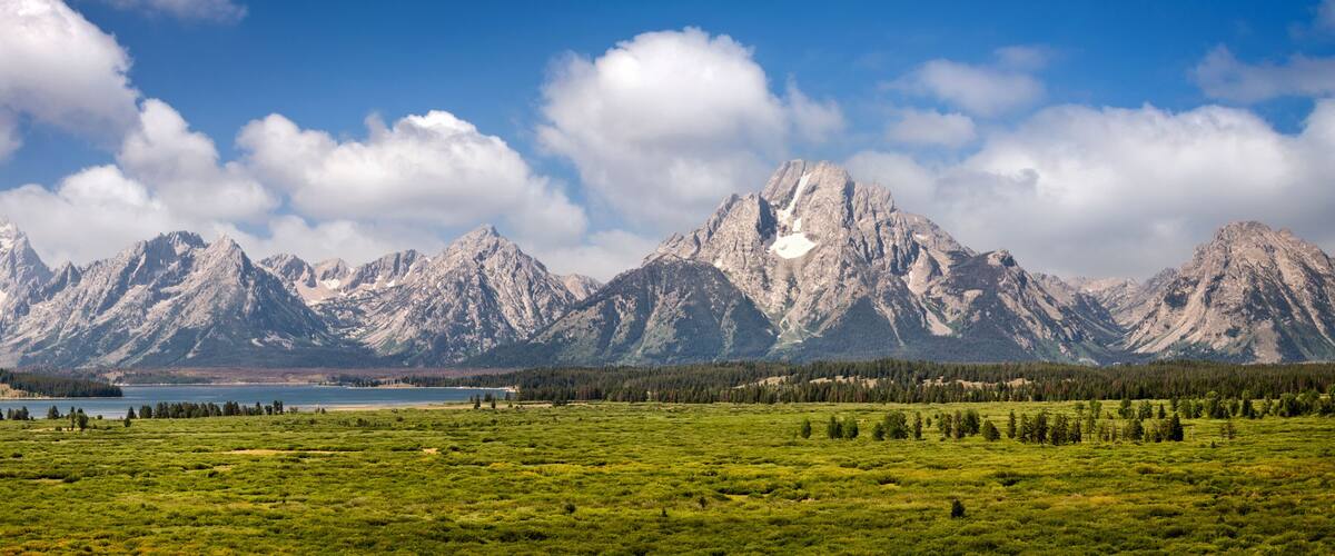 A mountain range with a lake in the foreground and a clear sky.