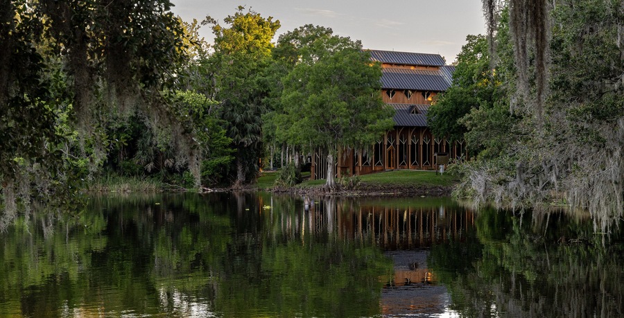 A lakeside building surrounded by trees and a calm body of water.